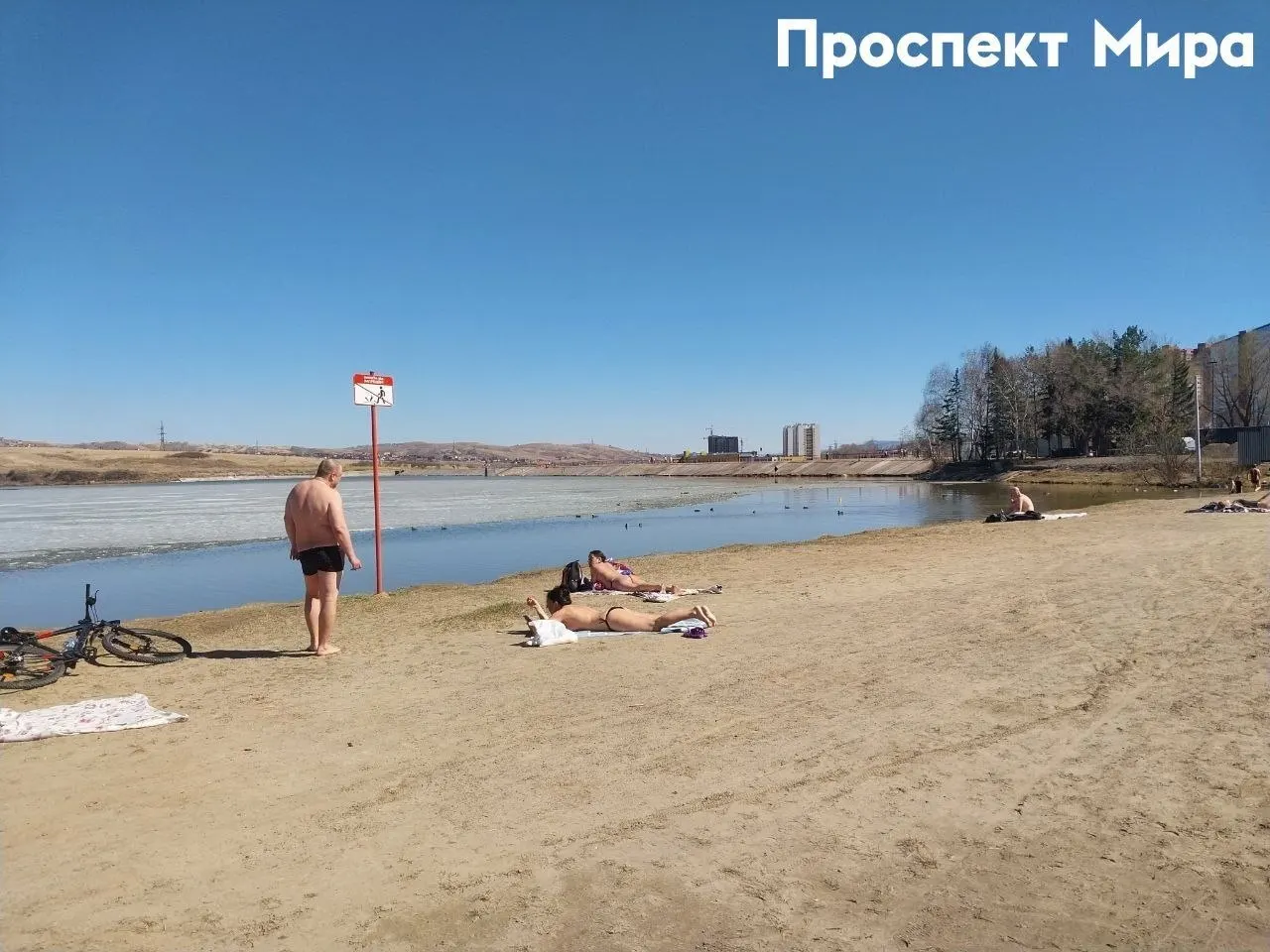 Местные жители вышли на пляж у озера на территории Мясокомбината, хотя часть воды ещё частично покрыта льдом.