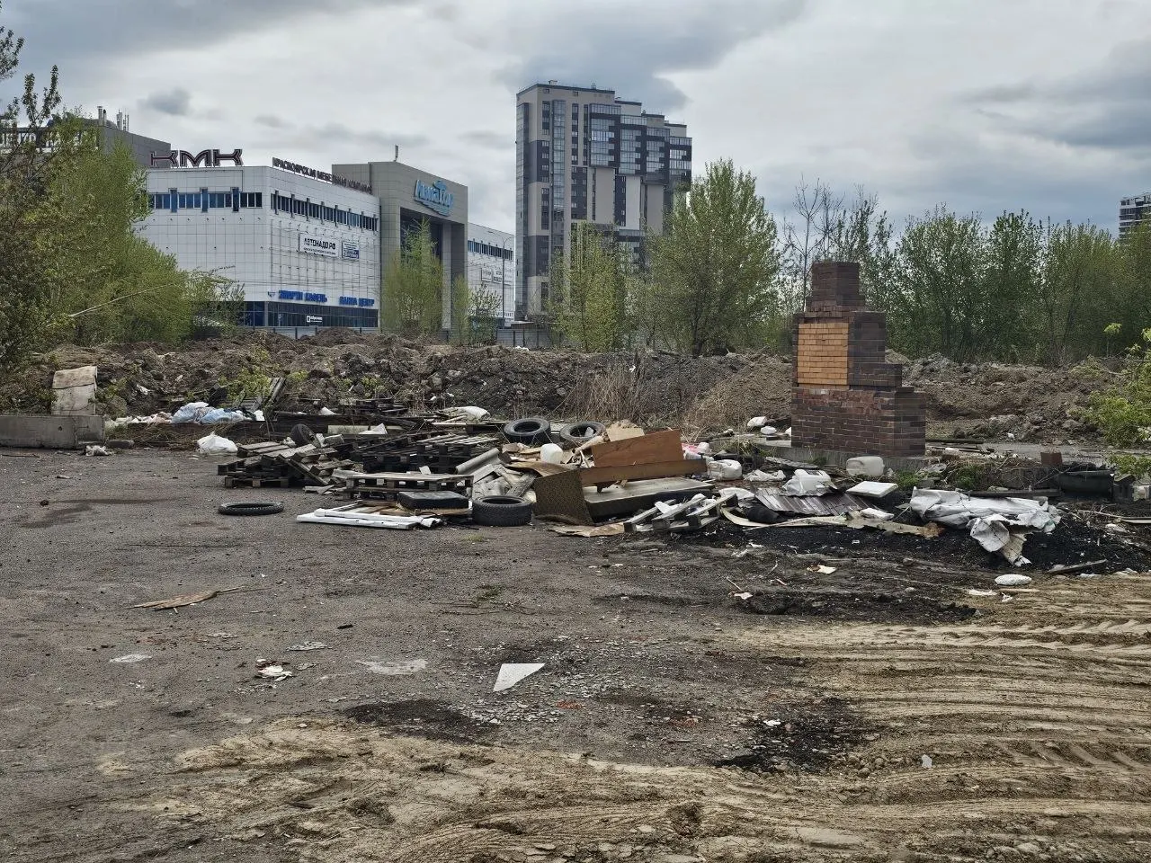 После демонтажа шиномонтажек, кафе и павильонов на улице Авиаторов территория завалена покрышками, строительными отходами и бытовым мусором. Из‑за отсутствия ограждений пыль летит к домам, а торчащая арматура и острые детали представляют опасность для детей; общественники обратились в прокуратуру.