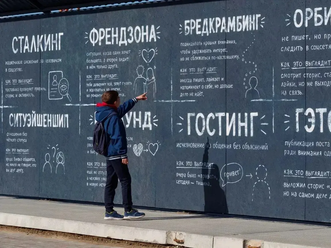 Ограда строящейся школы в «Кварталах Драверта» украшена разъяснениями для бумеров и зумеров: значение эмодзи, сленг и даже советы, как не смутиться от выражения «без четверти три».