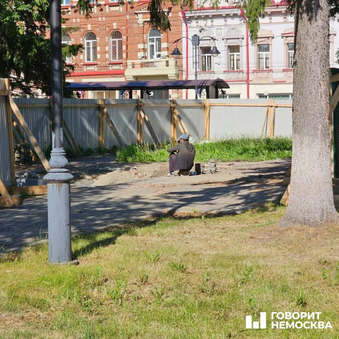 В огороженном Сквере Памяти в Томске рабочие и тяжёлая техника укладывают плитку на месте демонтированного Камня Скорби; жители требуют объяснений, власти говорят о переносе мемориалов без сроков.