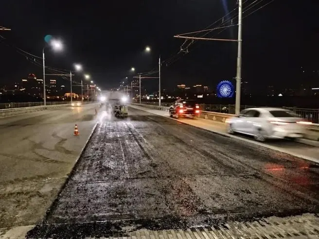 На Октябрьском мосту продолжаются работы по замене асфальта и подготовке к капитальному ремонту; ранее контракт был расторгнут за нарушение условий, сейчас работы продолжаются силами подрядчика.