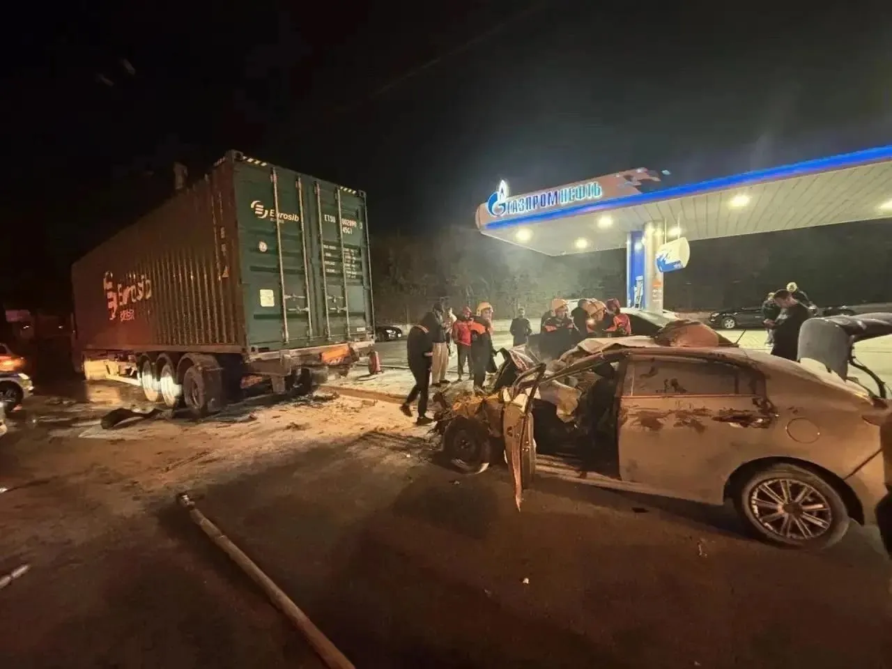 33-летний водитель на Kia Rio врезался в грузовик Volvo на заправке; водитель и пассажир с заднего сиденья госпитализированы, передний пассажир погиб на месте.
